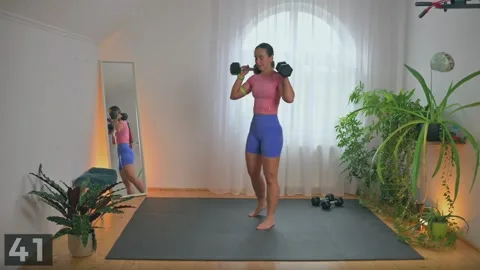 B-stance squat demonstration with two dumbbells