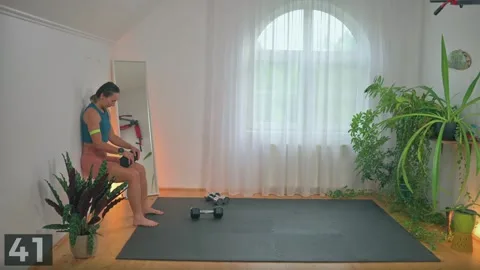 Wall sit demonstration with one dumbbell